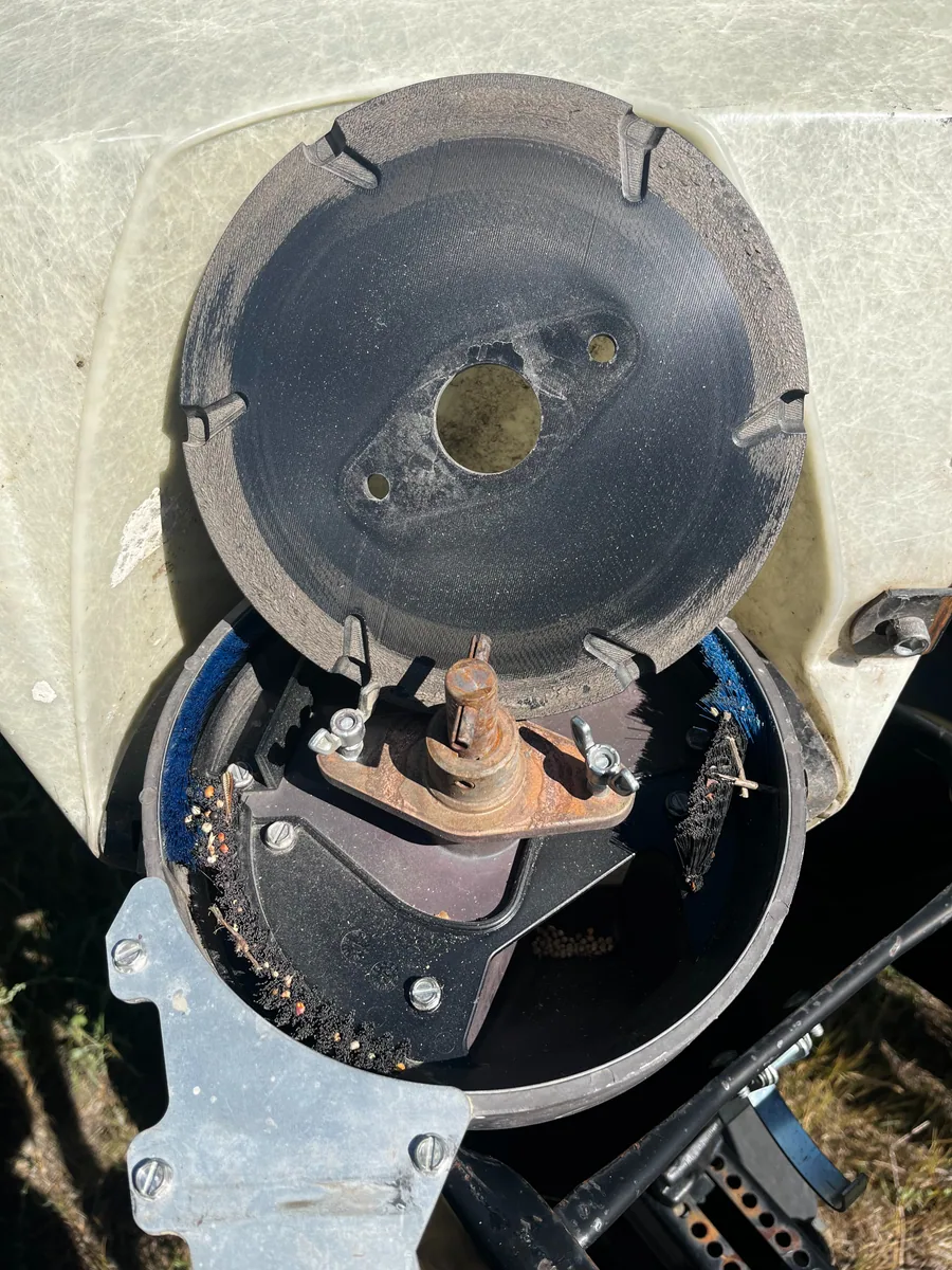White 3D-printed corn seed disc being installed in a planter meter